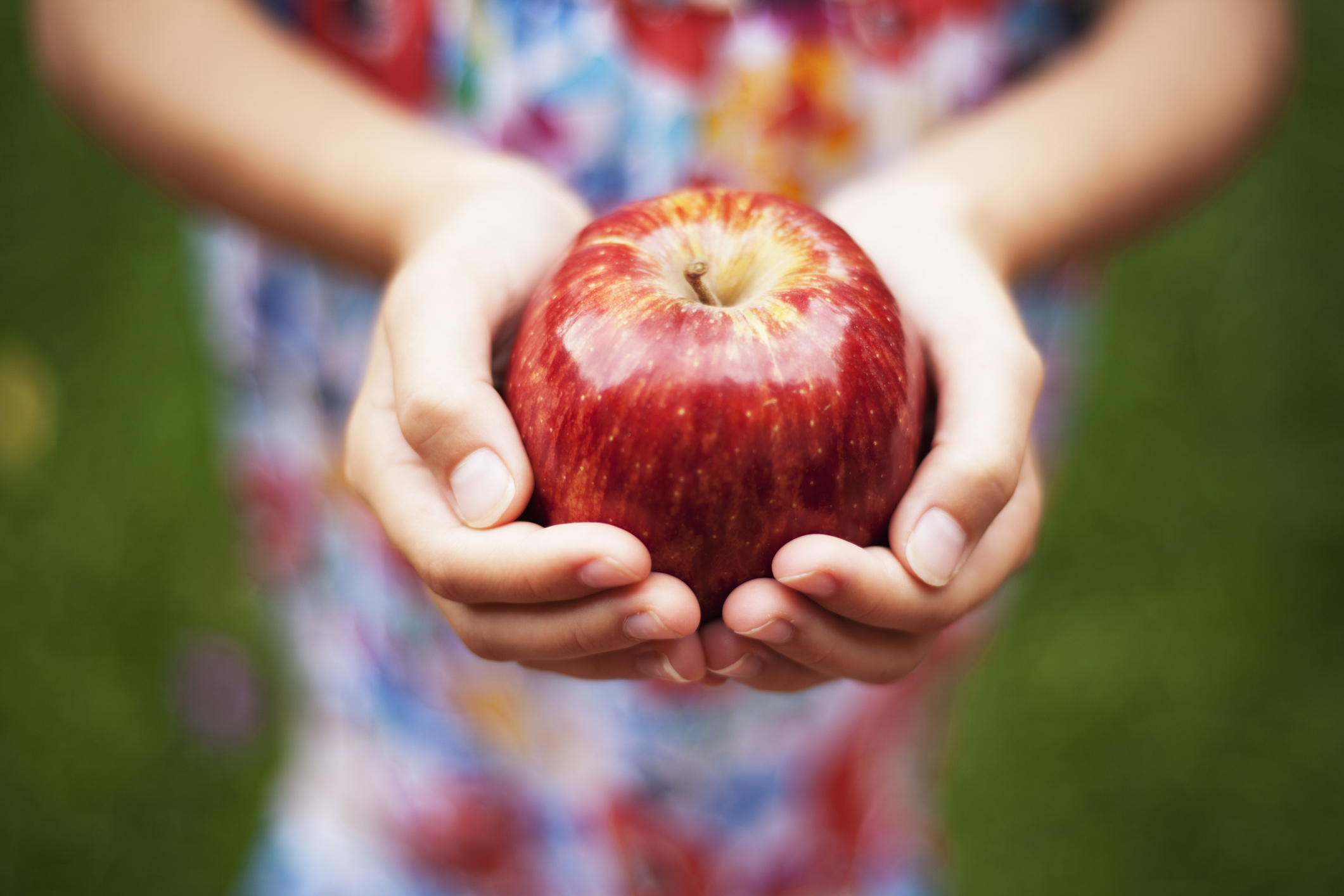 A girl holding a bright red apple.