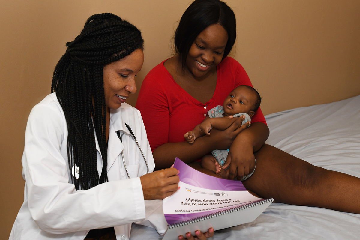 Mother holding young infant and speaking with a doctor