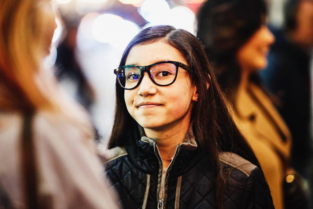 Image of a smiling teenage girl outside with friends on a cold evening.