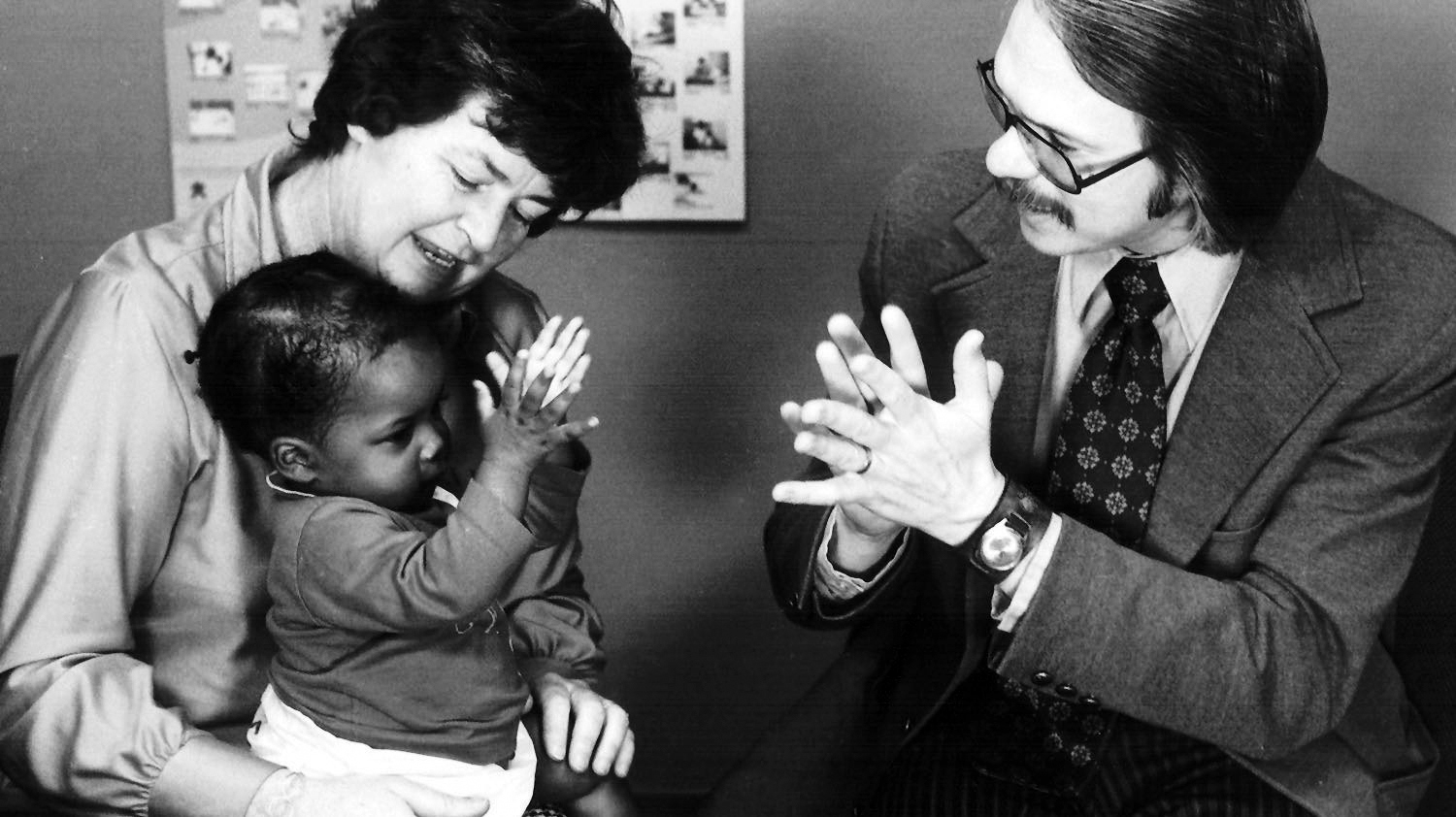 Caregivers clapping with baby.