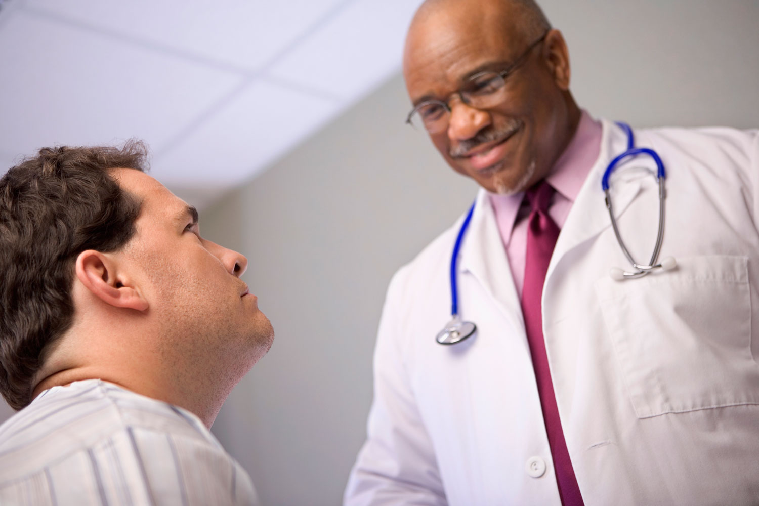 Smiling doctor talking with man in a hospital room.