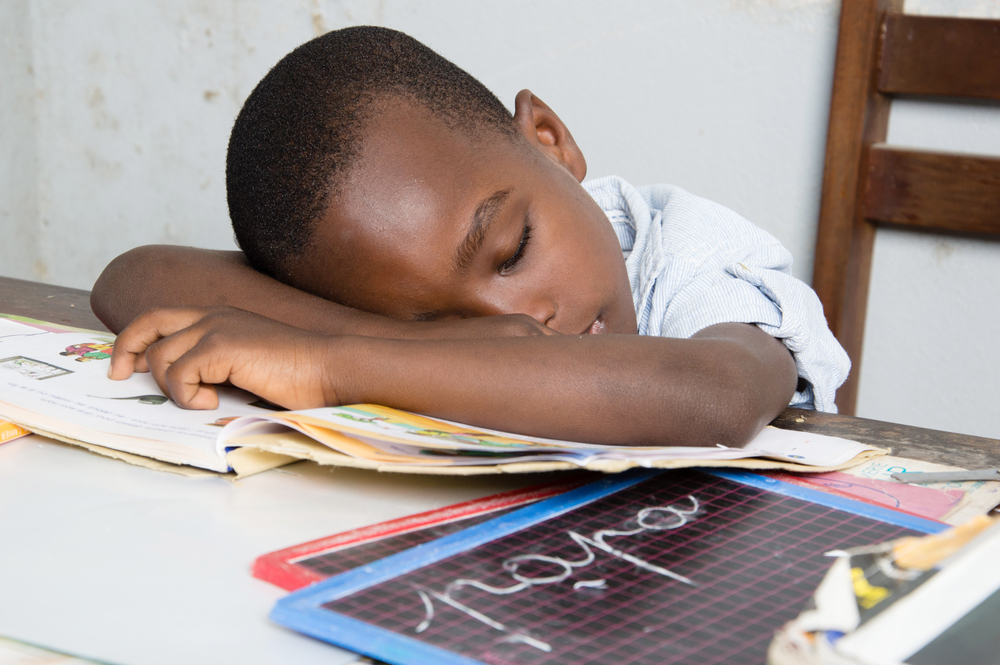 Boy asleep at a desk with his head on a book Boy asleep at a desk with his head on a book