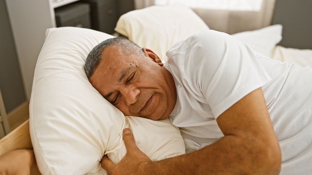 Mature Latino man sleeping peacefully in bed.