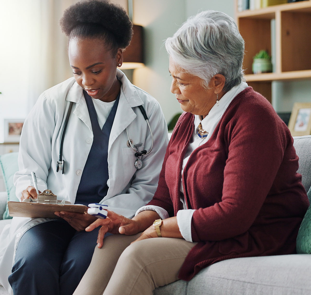 Elderly Latina woman speaking to a young Black woman doctor.