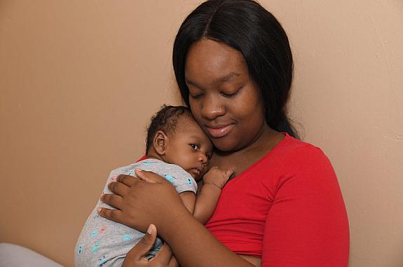 Mother holding a baby and looking content.