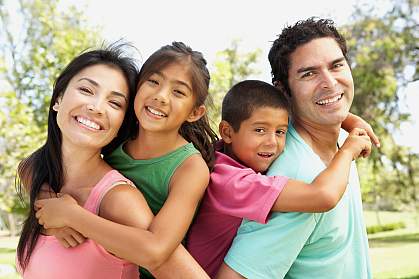 A happy family of four. The two children are piggy-backing on their parents.