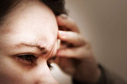 Photo of a woman holding her hand to her head