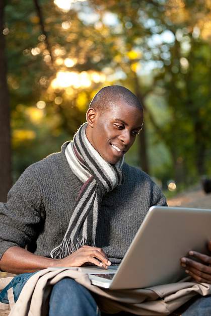 Photo of a young African-American man looking at a computer and smiling