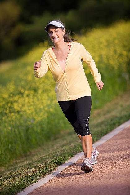 Photo of an older woman walking briskly around a track