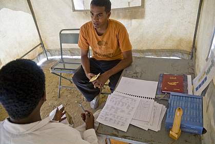 Photo of an young man talking with a doctor in a mobile clinic tent in Africa