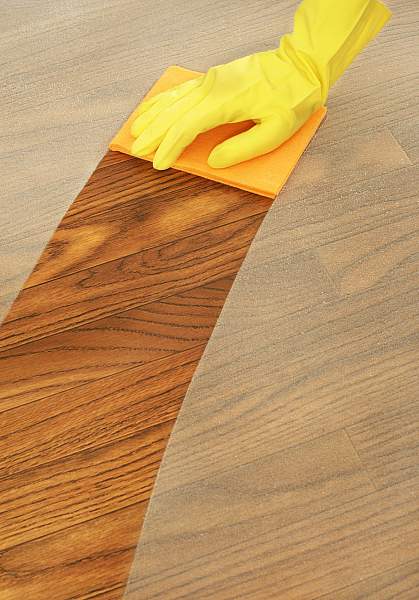 Person dusting a wood table with a cloth.