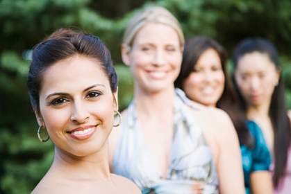 A woman smiling, with other woman in the background.