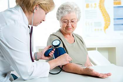 Female doctor measuring blood pressure of senior woman.