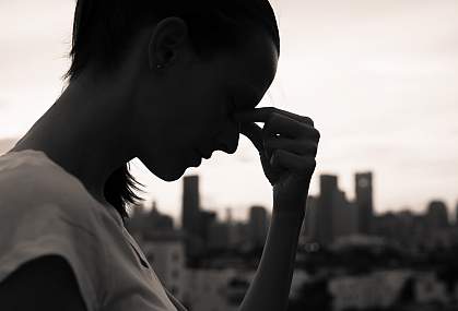 Silhouette of a woman resting her head in her hands.