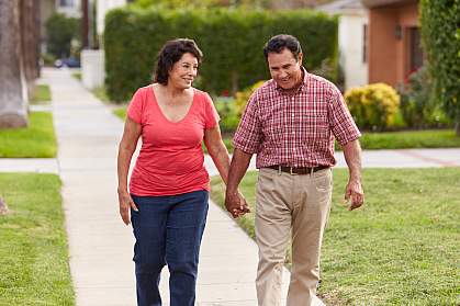 Senior Hispanic couple walking and holding hands on a sidewalk