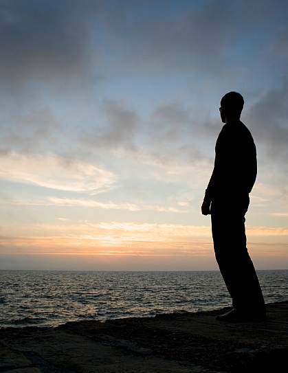 Silhouette of man watching sunrise off a pier