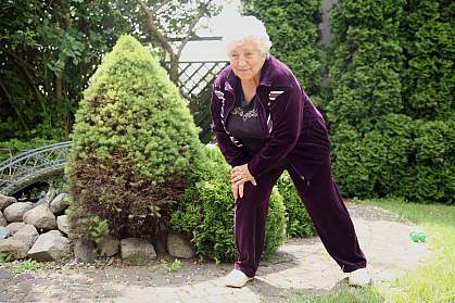 Overweight senior woman exercising in purple velour tracksuitOverweight senior woman exercising in purple velour tracksuit