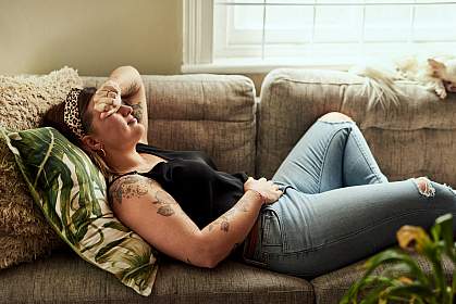 Woman lying on sofa holding her stomach