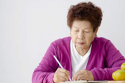 Asian senior woman writing in book