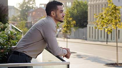 Businessman standing at balcony railing and looking down on a city street