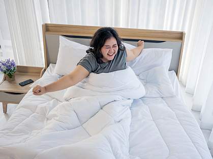 Woman stretching in bed after waking up