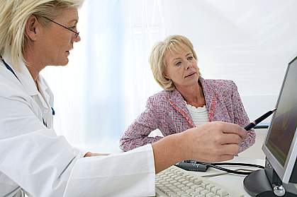 Doctor pointing to a computer screen explaining something to a patient Doctor pointing to a computer screen explaining something to a patient