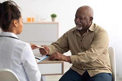 Black female doctor giving an elderly male patient pills Black female doctor giving an elderly male patient pills