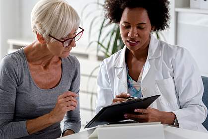 Female doctor speaking with an elderly female patient while looking at test results.