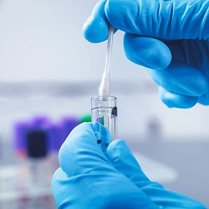 Close up of a swab being inserted into a test tube