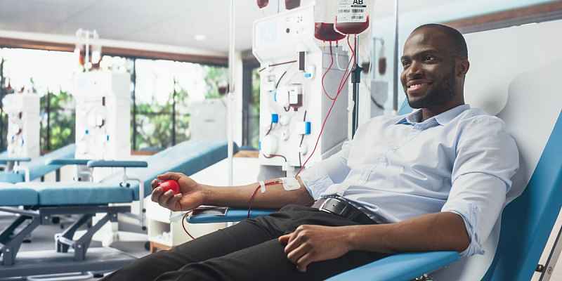 A young African American man smiling as he donates blood.