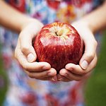 A girl holding a bright red apple.