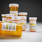 Variety of Non-Proprietary Medicine Bottles on Reflective Surface and Grey Background.