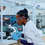 Image of a scientist checking a sample through a microscope.