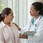 A female doctor comforts a female patient.