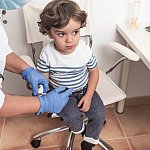 Paediatrician takes blood sample from toddler to check glucose levels.