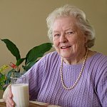 Photo of an older woman with a glass of milk.