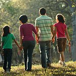 Rear view photo of a family walking together in a park.