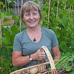 Happy woman with a wicker basket full of fresh vegetables.