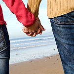 Couple holding hands on beach in winter