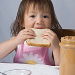 Girl eating a peanut butter sandwich.