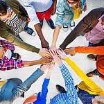 Circle of diverse people joining hands in the center.