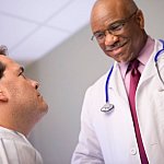 Smiling doctor talking with man in a hospital room.