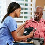 Nurse taking senior man’s blood pressure.