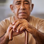 Portrait of a senior man with his hands on a cane.