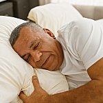 Mature Latino man sleeping peacefully in bed.