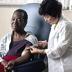 A nurse administering chemotherapy a woman through a catheter.